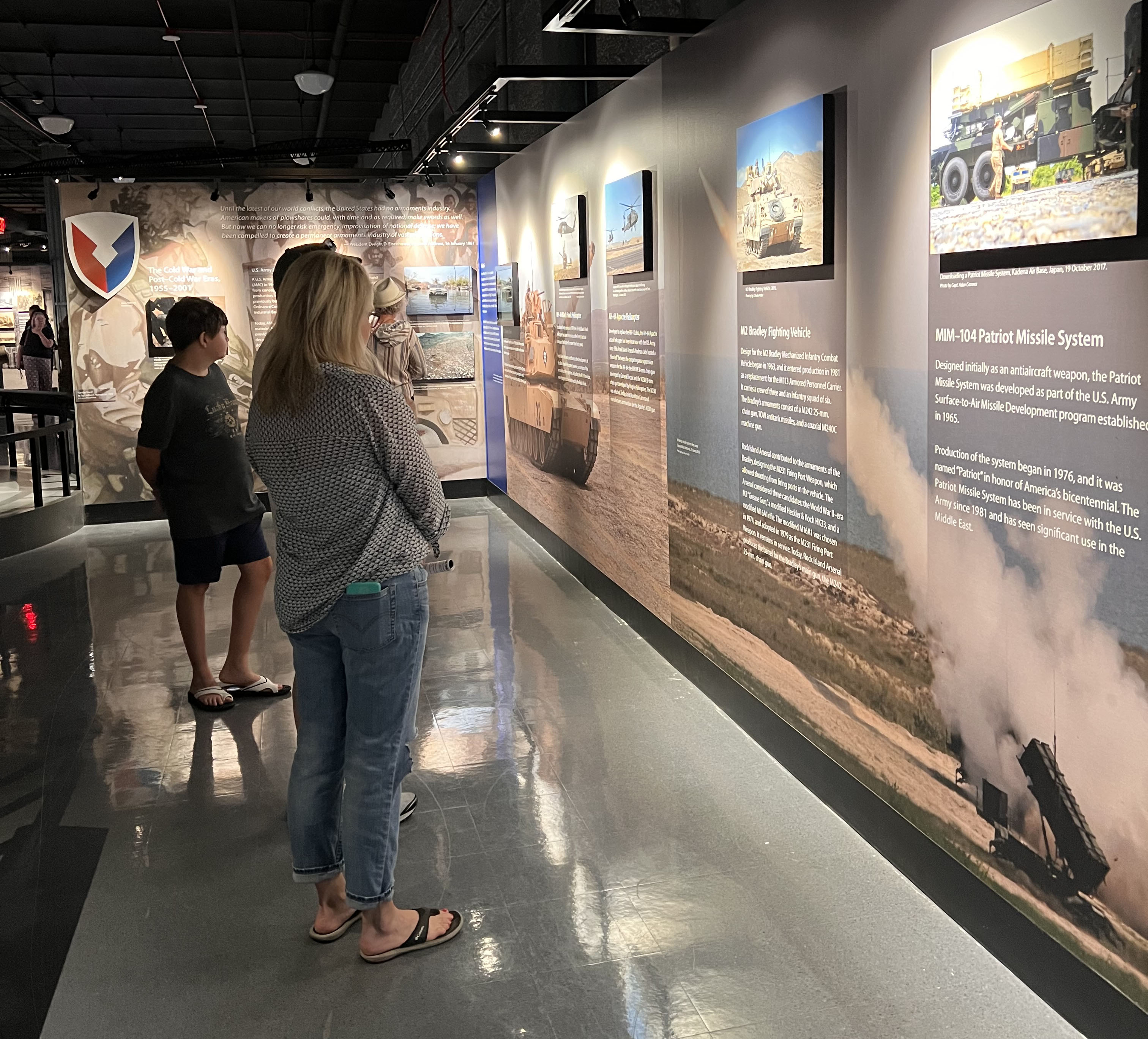 Several people reading from a museum exhibit wall.